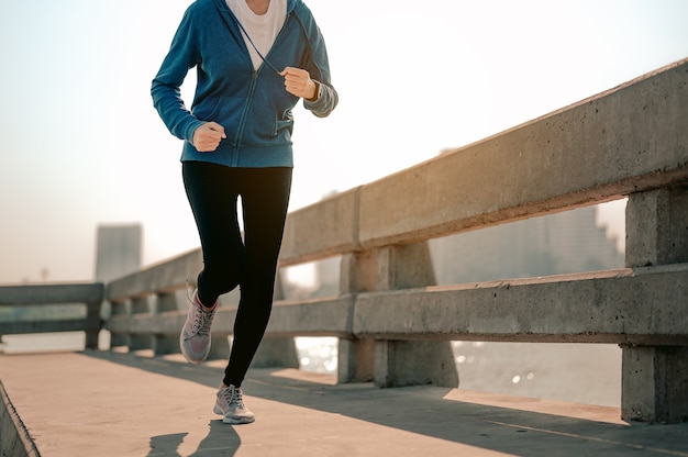 Primo piano delle gambe giovani donne asiatiche che fanno jogging durante l'allenamento mattutino in città Una città che vive in salute