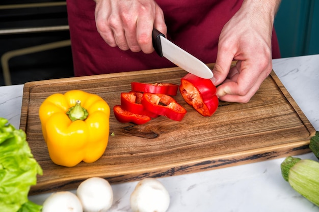 Primo piano delle mani che tagliano le verdure con il coltello.