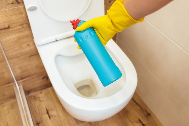 Primo piano delle mani che utilizzano la soluzione di pulizia della toilette disinfettante mockup di bottiglia blu