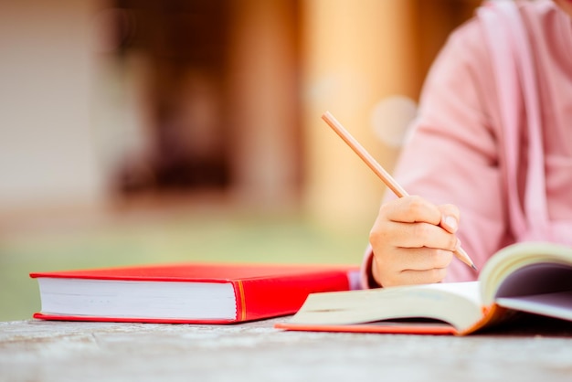 Primo piano delle mani degli studenti con libri che scrivono su quaderni. istruzione e concetto di scuola