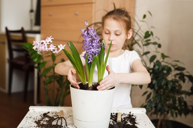 Primo piano delle mani dei bambini che ripiantano i fiori che sbocciano in un vaso di fiori