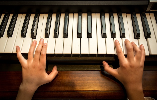 Primo piano delle mani del bambino che suonano il pianoforte