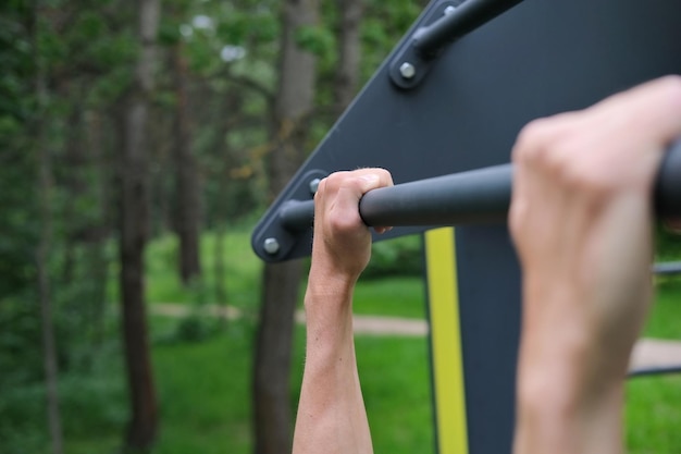 primo piano delle mani dell'uomo atletico sulla barra pullup durante l'esercizio pullup in allenamento