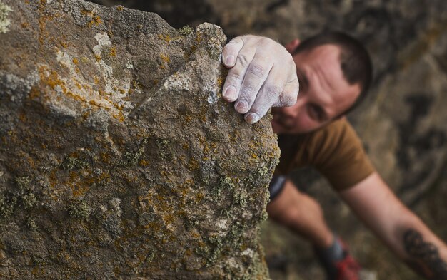 Primo piano delle mani dell'uomo in polvere di gesso magnesio su roccia. Extreme scala una roccia su una corda con la massima assicurazione