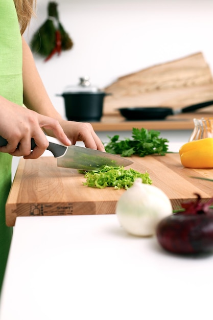 Primo piano delle mani della donna che cucinano in cucina. Casalinga che affetta l'insalata fresca Concetto di cucina vegetariana e sana.