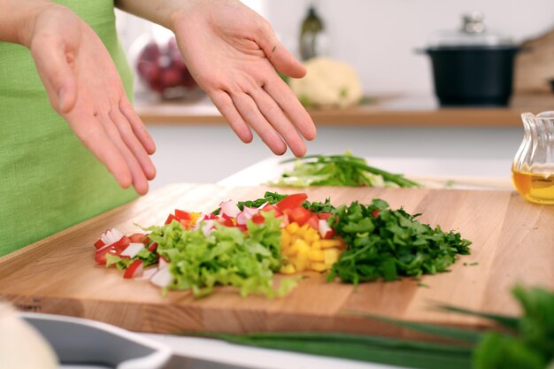 Primo piano delle mani della donna che cucinano in cucina Casalinga che offre insalata fresca Concetto di cucina vegetariana e salutare