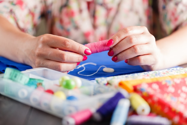 Primo piano delle mani della donna che cucono un bottone