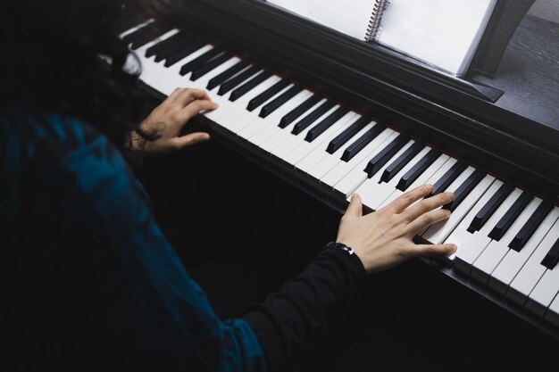 Primo piano delle mani della donna che suonano il pianoforte leggendo spartiti. Messa a fuoco selettiva