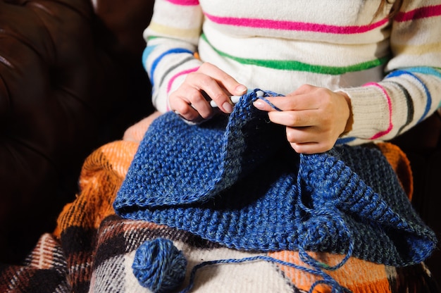 Primo piano delle mani della donna che tricottano il filato di lana variopinto