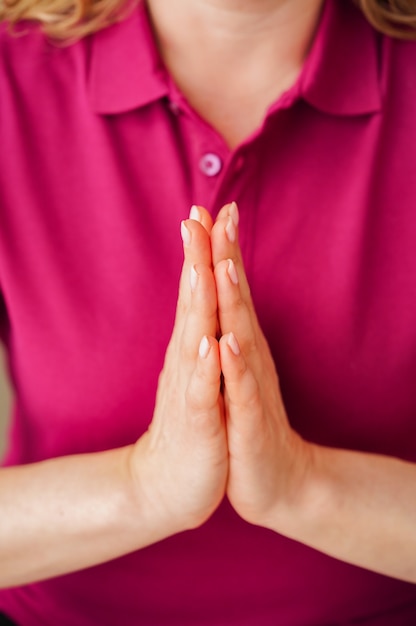 Primo piano delle mani della donna con i palmi uniti in posizione di preghiera