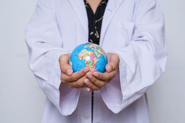 Primo piano delle mani della dottoressa in abito medico che tiene la Terra per salvare il concetto del mondo.