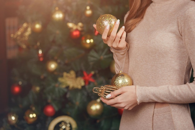 Primo piano delle mani delle donne con palloncini sullo sfondo di un albero di Natale