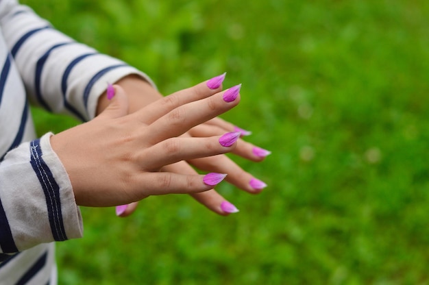 Primo piano delle mani delle donne petali viola di geranio selvatico sono incollati sulle unghie