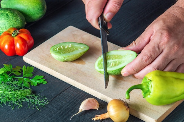 Primo piano delle mani dello chef che tagliano un cetriolo fresco Cucinare l'insalata nella cucina del ristorante