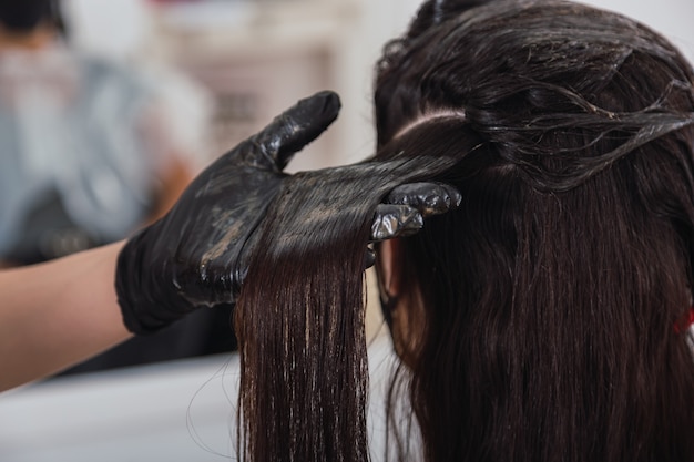 Primo piano delle mani di un parrucchiere che tinge i capelli.