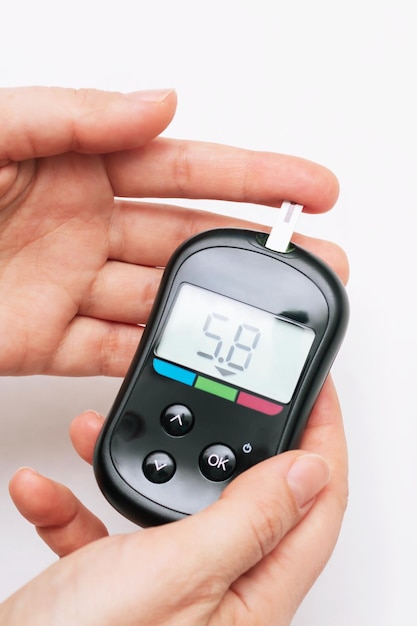 Primo piano delle mani di una donna che utilizza un glucometro per misurare la glicemia Il tester del diabete