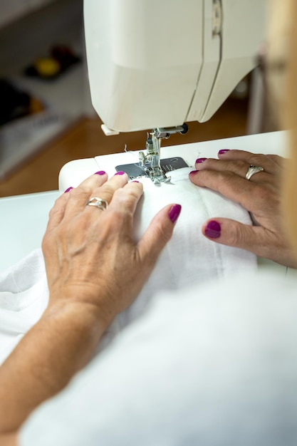 Primo piano delle mani di una donna irriconoscibile che cuce sulla sua macchina da cucire