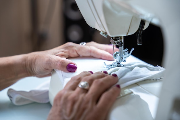 Primo piano delle mani di una donna irriconoscibile che cuce sulla sua macchina da cucire