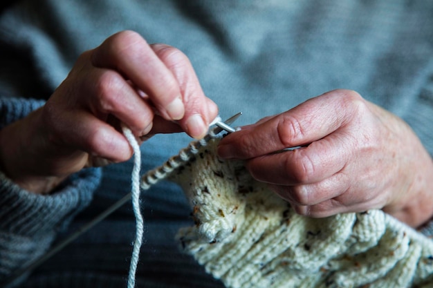 Primo piano delle mani di una donna più anziana che lavorano a maglia un ponticello