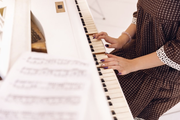 Primo piano delle mani femminili che giocano la tastiera del piano