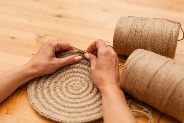 Primo piano delle mani femminili che lavorano a maglia un prodotto di iuta Creatività fatta a mano dal concetto di materiali naturali Hobby ricamo