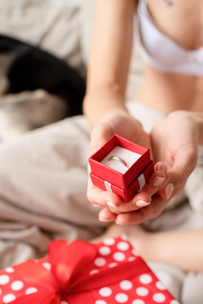 Primo piano delle mani femminili che tengono giftbox rosso con anello