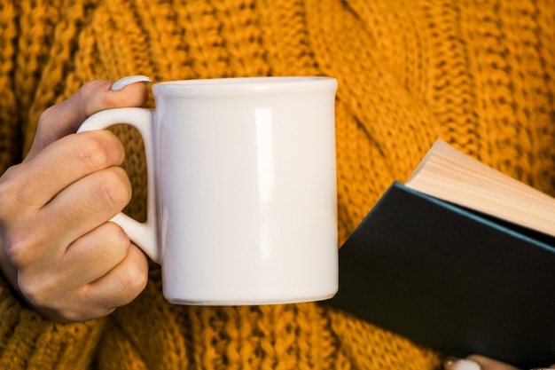 primo piano delle mani femminili con una tazza di bevanda bella donna in maglione urlante che tiene tazza di tè