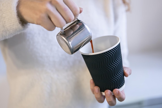 Primo piano delle mani femminili dei baristi che versano l'espresso in un bicchiere