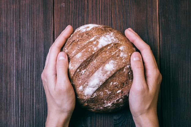 Primo piano delle mani femminili disposte sul tavolo di pane fresco