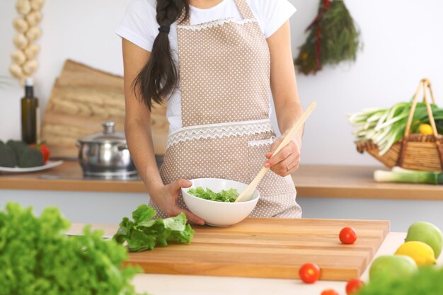Primo piano delle mani umane che cucinano insalata di verdure in cucina Pasto sano e concetto vegetariano