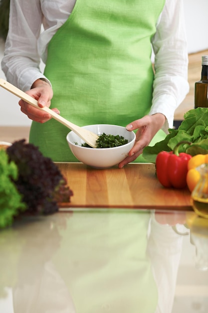 Primo piano delle mani umane che cucinano insalata di verdure in cucina sul tavolo di vetro con la riflessione. Pasto sano e concetto vegetariano