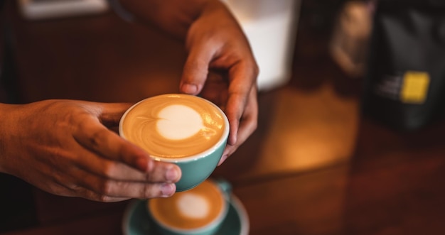 Primo piano delle mani uomo barista che serve caffè nella caffetteria. mani maschili che mettono una tazza di caffè sul tavolo. Caffè, barista, estrazione, servizio, caffetteria, concetto di stile di vita.