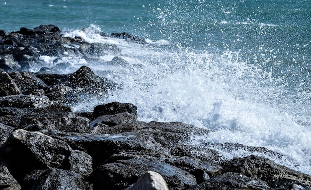 Primo piano delle onde del mare che si infrangono sulle rocce della spiaggia di Vilanova y la Geltru.