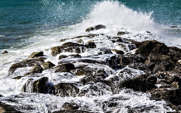 Primo piano delle onde del mare che si infrangono sulle rocce della spiaggia di Vilanova y la Geltru.