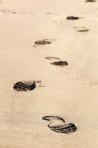 Primo piano delle orme nella sabbia sulla spiaggia.