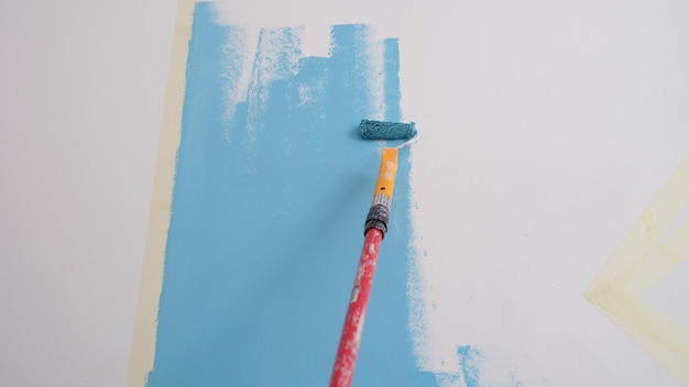 Primo piano delle pareti della pittura del decoratore in colore azzurro con la decorazione interna del rullo o