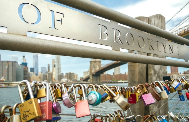 Primo piano delle serrature d'amore nel recinto con il ponte di Brooklyn di New York sullo sfondo