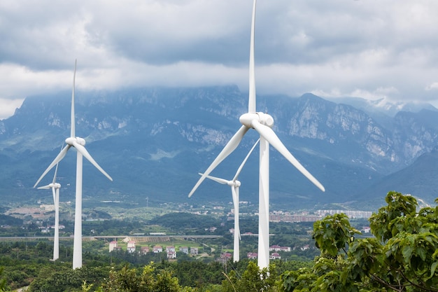 Primo piano delle turbine eoliche con sfondo di montagna lussureggiante Cina