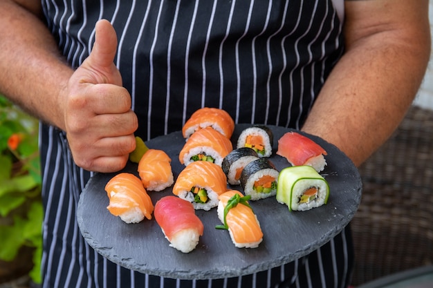 Primo piano dello chef che tiene il vassoio del cibo con un pezzo di sushi