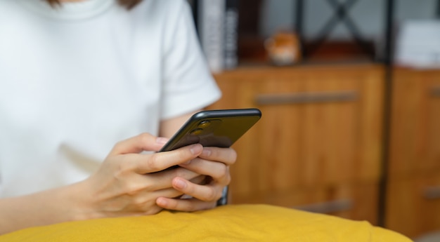 Primo piano dello smartphone della tenuta della mano della giovane donna e chiacchierare con gli amici alla rete sociale.