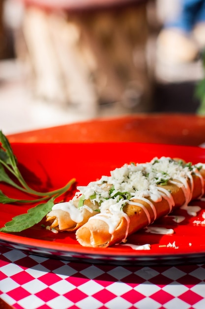 Primo piano di alcuni deliziosi tacos fritti messicani con formaggio e panna