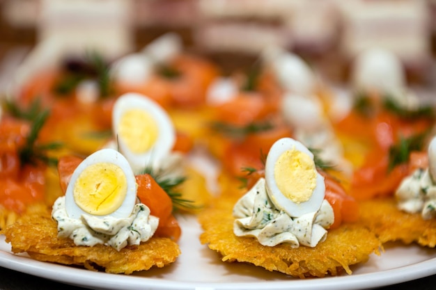 Primo piano di antipasti di frittelle di patate uova e frutti di mare allineati sul tavolo del partito