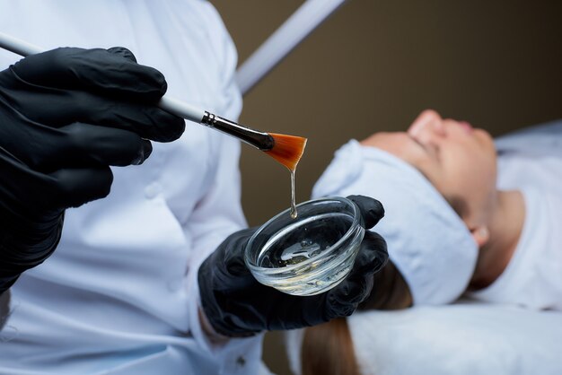 primo piano di appendere goccia di peeling viso trasparente sul pennello sopra la tazza.