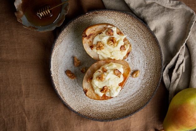 Primo piano di appetitose pere grigliate dolci con noci e miele autunnale dessert rustico