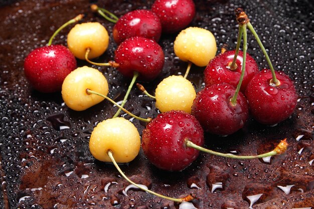 Primo piano di bacche di ciliegie fresche con gocce d'acqua Composizione di ciliegie dolci su uno sfondo scuro con gocce d'acqua vista dall'alto