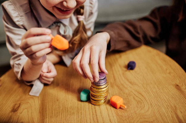 Primo piano di bambini che impilano monete di cioccolato mentre giocano allo spazio di copia del gioco dreidel ebraico