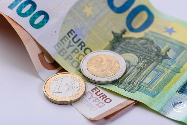 Primo piano di banconote e monete in euro su sfondo bianco Valuta dell'Unione europea