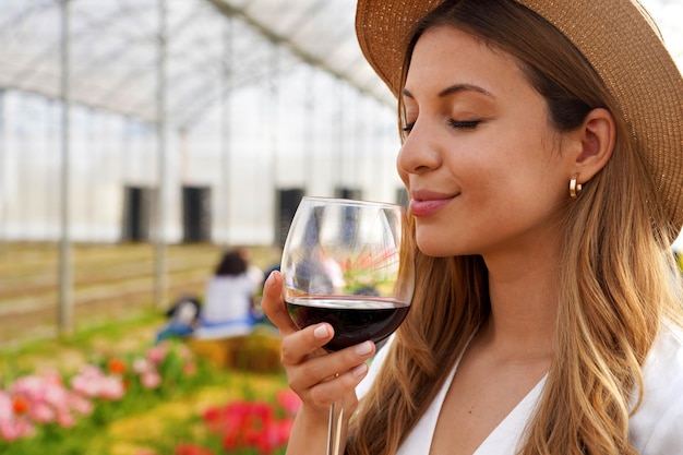 Primo piano di bella donna che sente l'odore del vino rosso dal vetro con gli occhi chiusi