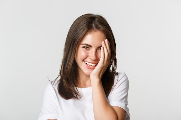 Primo piano di bella donna sorridente che guarda civettuola alla macchina fotografica sopra bianco