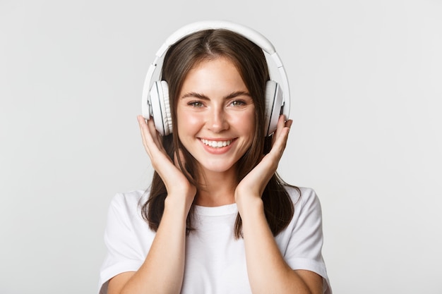 Primo piano di bella ragazza felice sorridente, godendo l'ascolto di musica in cuffie senza fili.